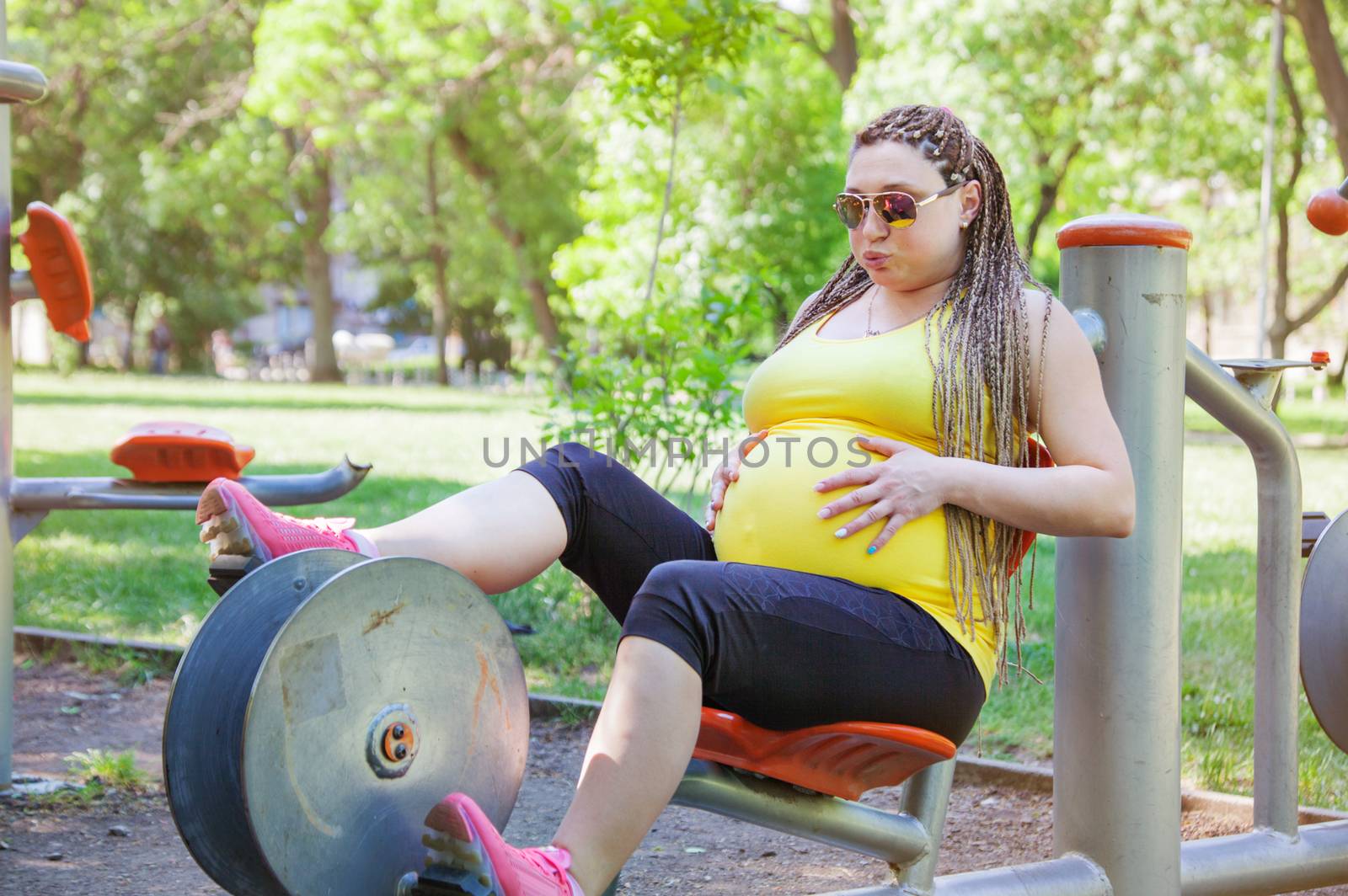 Pregnant woman on a cycling exercise machine in the park.