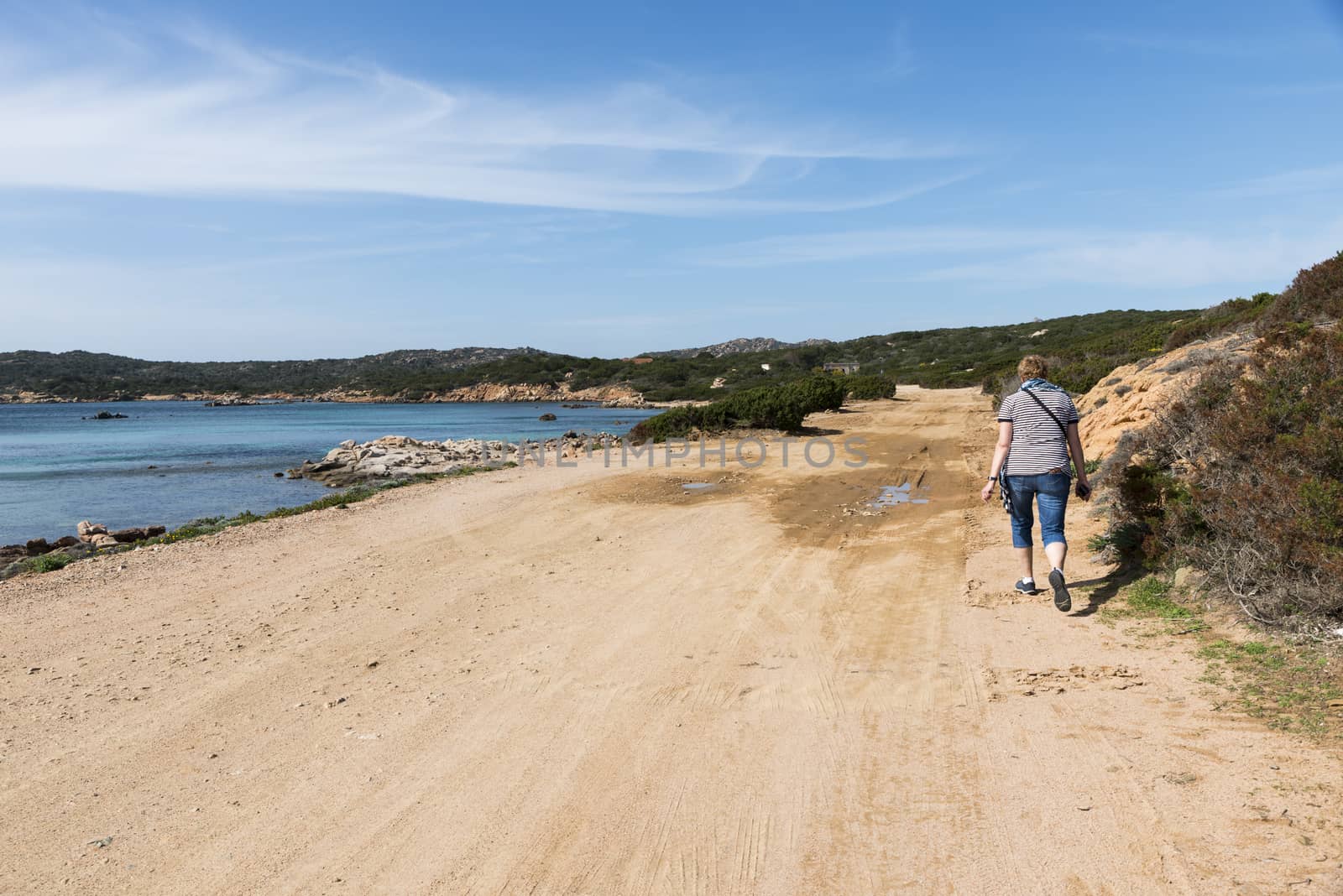 Caprera,Italy,07-april-2018:Adult womand walking along the roads of Caprera island, this island belongs to the maddalena archipel and you can reach it by bridge from maddalena