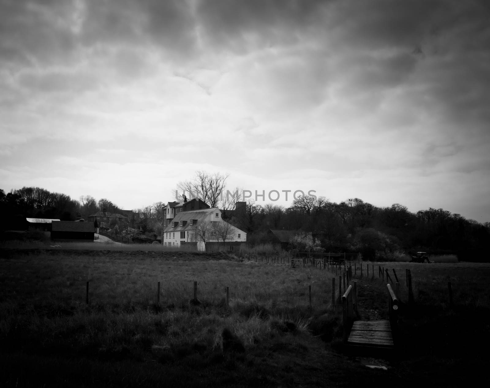 White farm house cottage mansion far off field trail bridge country environment nature black and white by callumrc