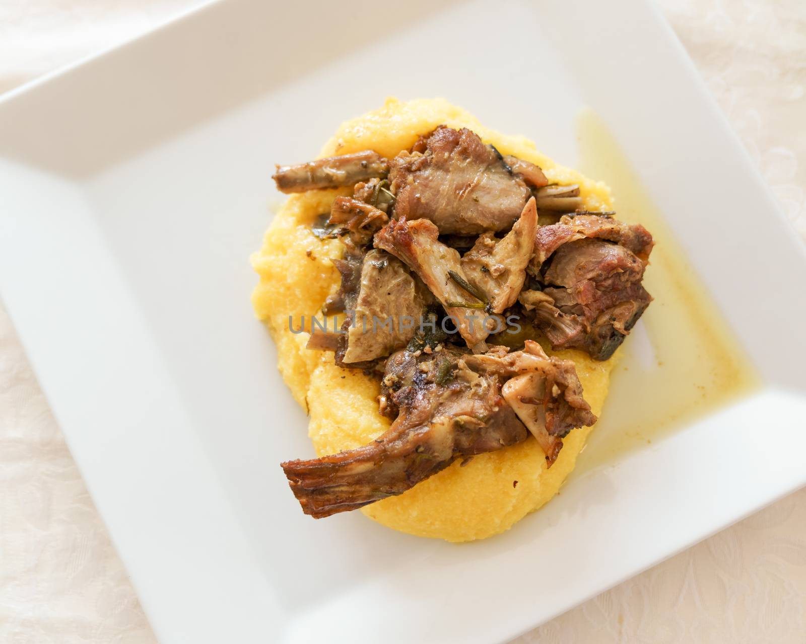 Typical italian food,polenta with Capretto( small goat meat) roasted, view from above.