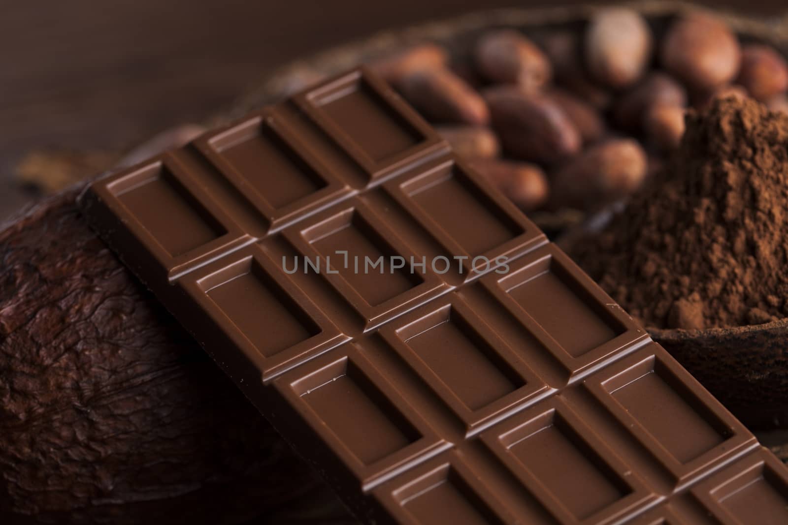 Chocolate bar, candy sweet, cacao beans and powder on wooden background