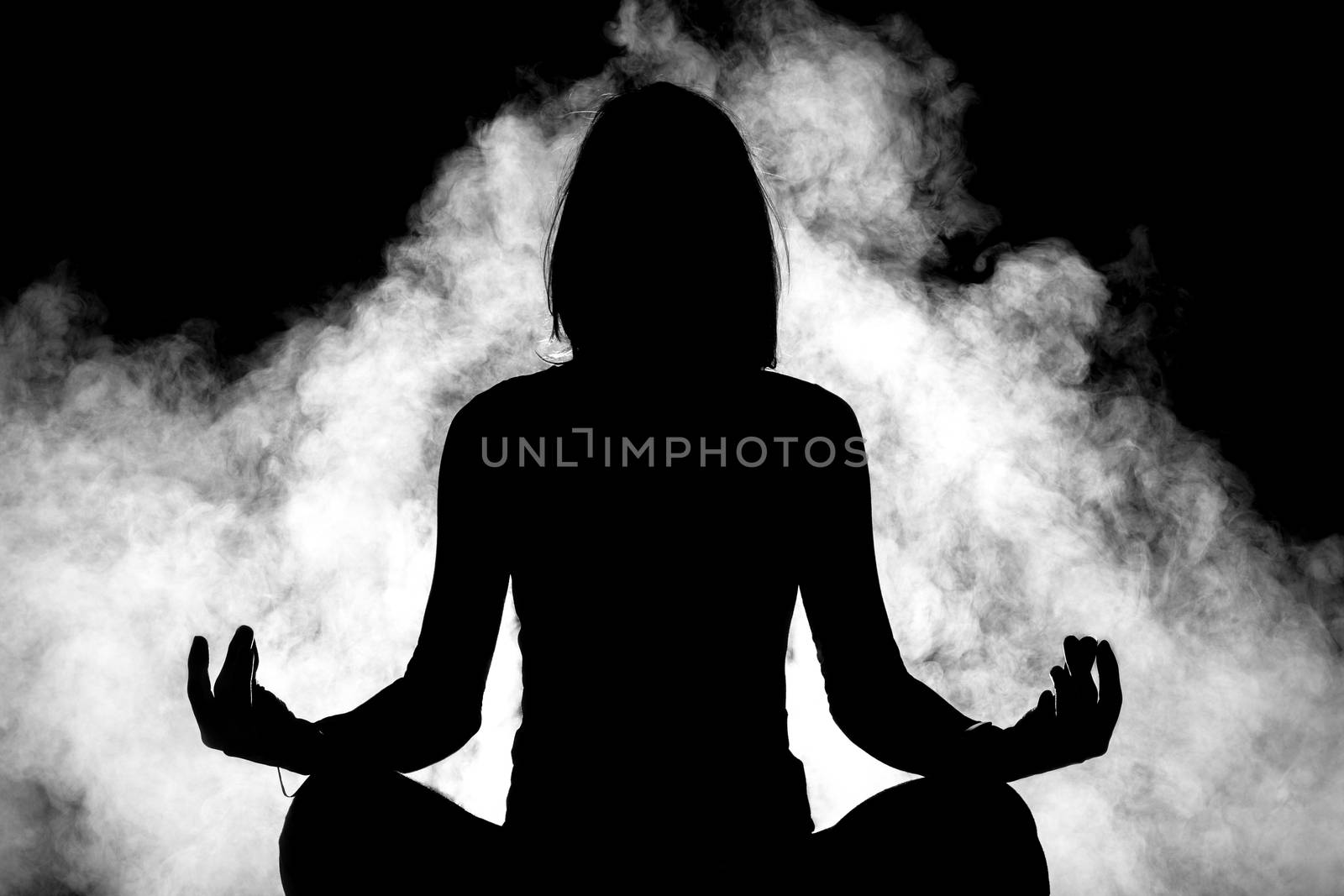 silhouette of girl practicing yoga with smoke in the background