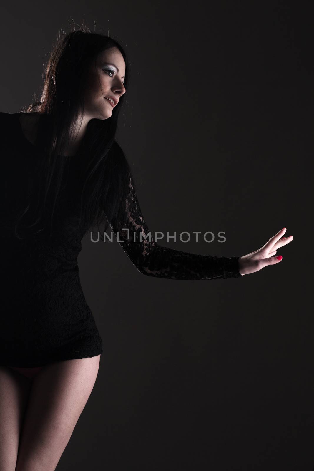 beautiful girl in black sexy clothes, against dark background