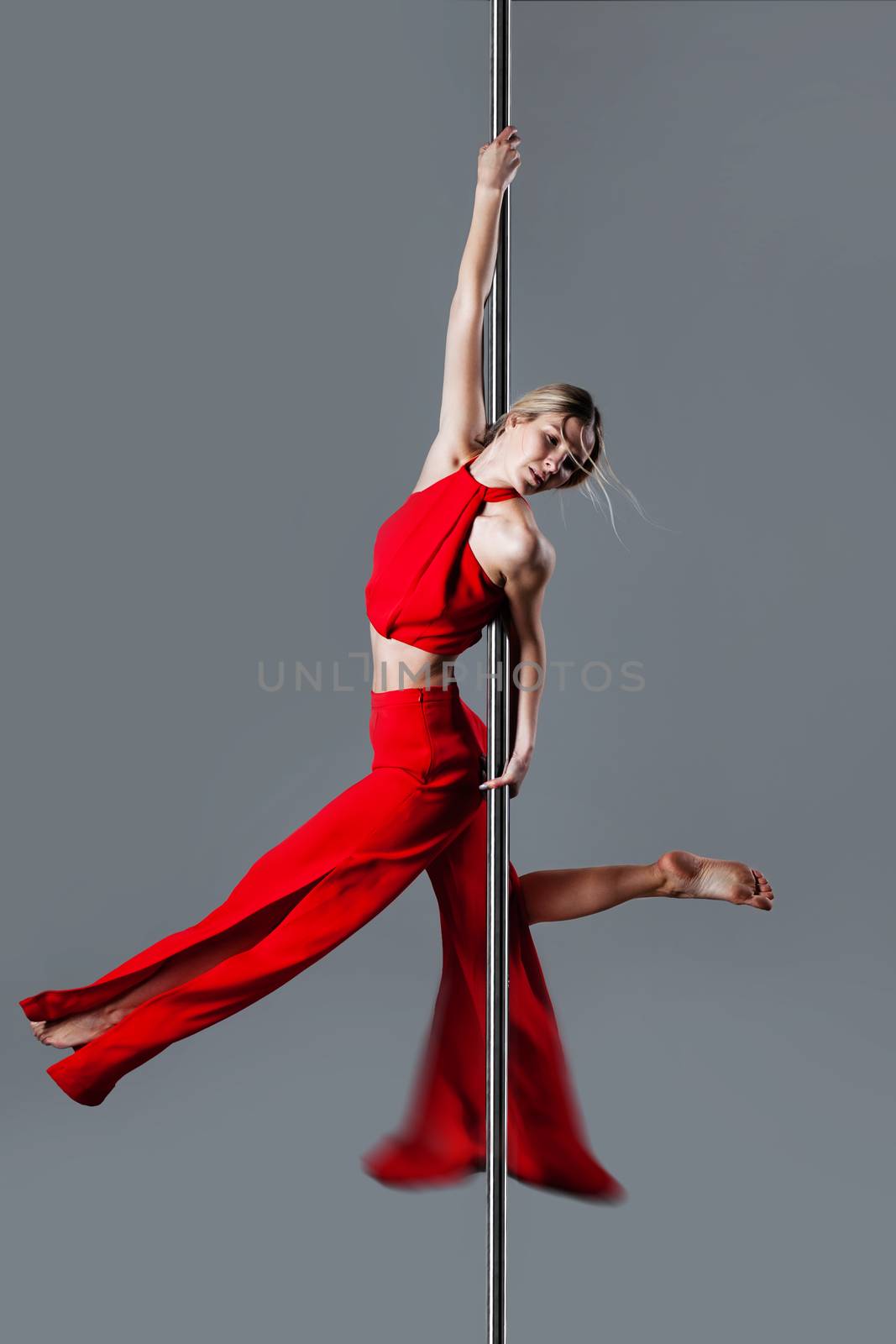 pole dance girl in elegant red outfit posing against gray background