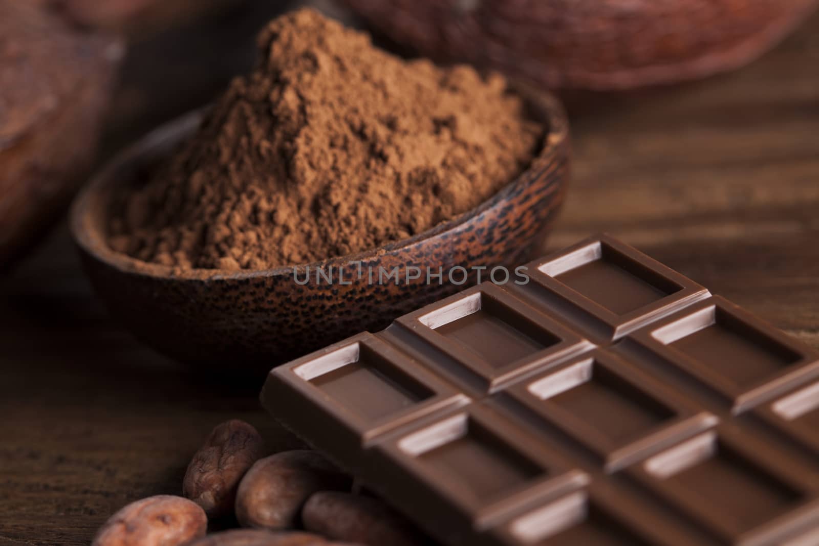 Chocolate bar, candy sweet, cacao beans and powder on wooden bac by JanPietruszka