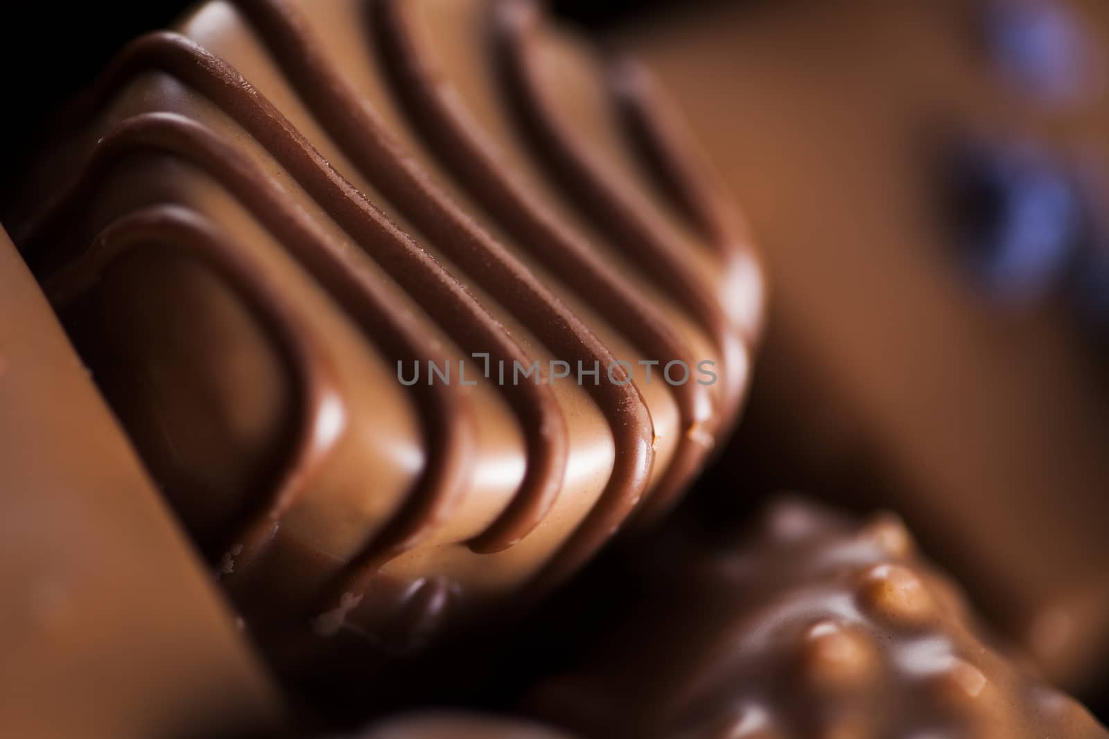 Chocolate bars and pralines on wooden background by JanPietruszka