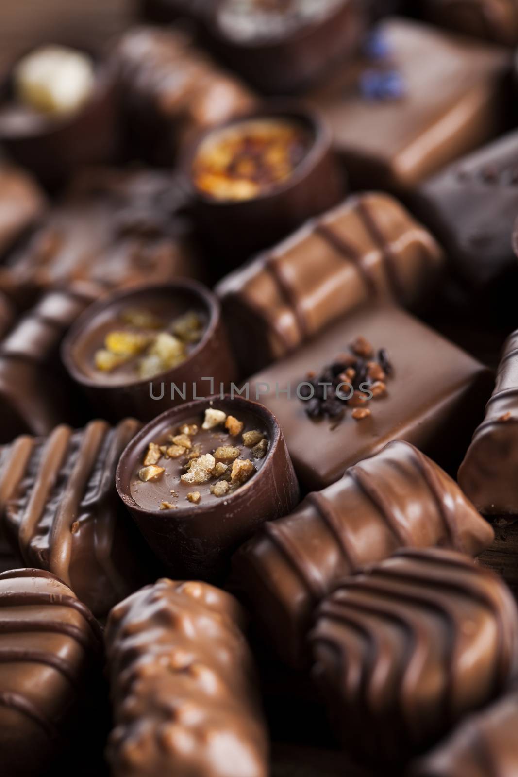 Chocolate bars and pralines on wooden background by JanPietruszka