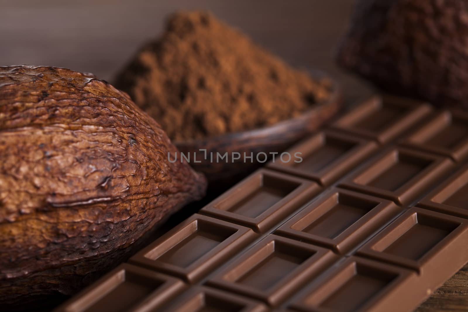 Chocolate bar, candy sweet, cacao beans and powder on wooden bac by JanPietruszka