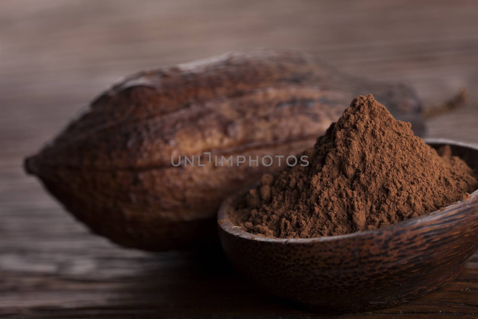 Cocoa beans in the dry cocoa pod fruit on wooden background by JanPietruszka