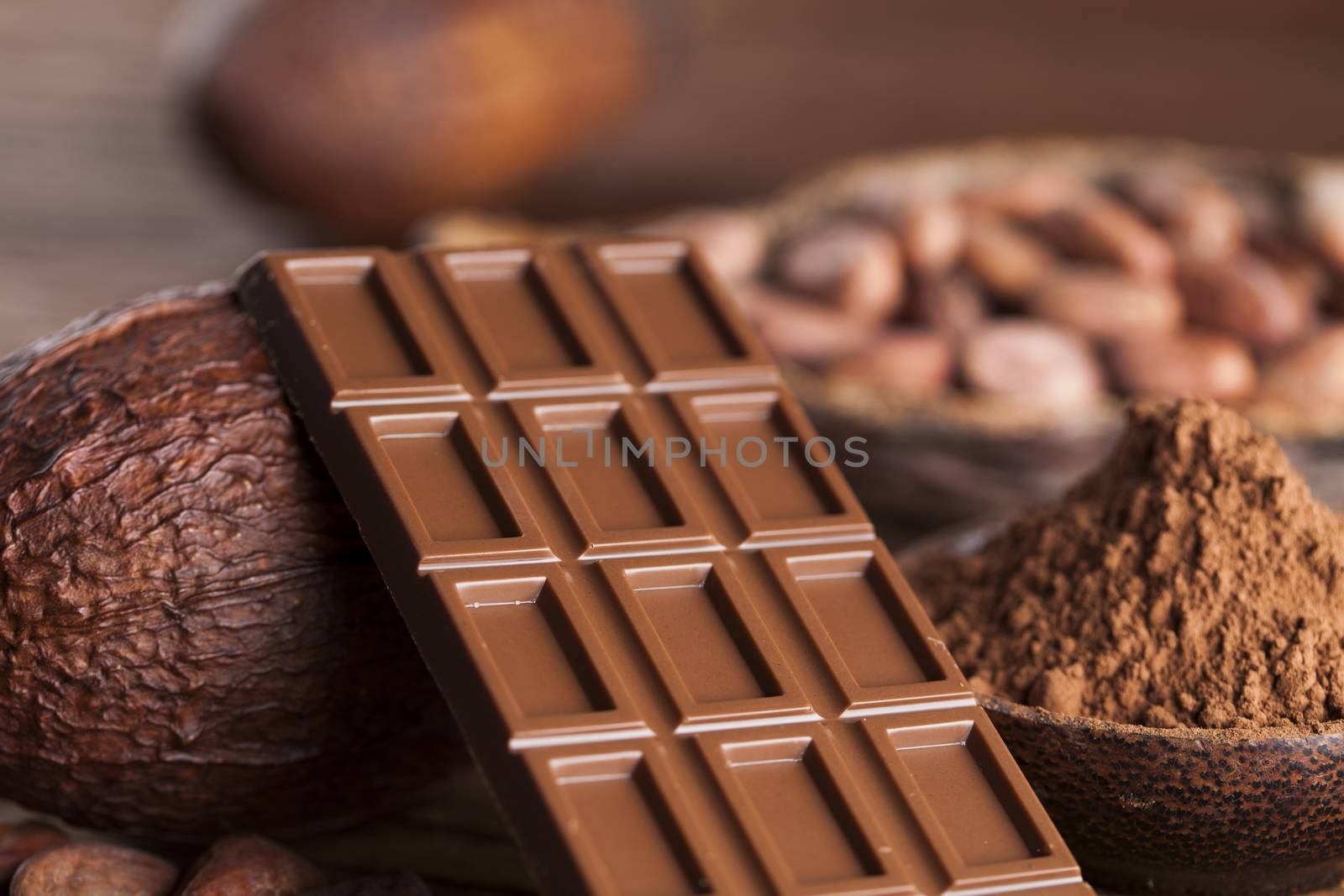 Chocolate bar, candy sweet, cacao beans and powder on wooden background