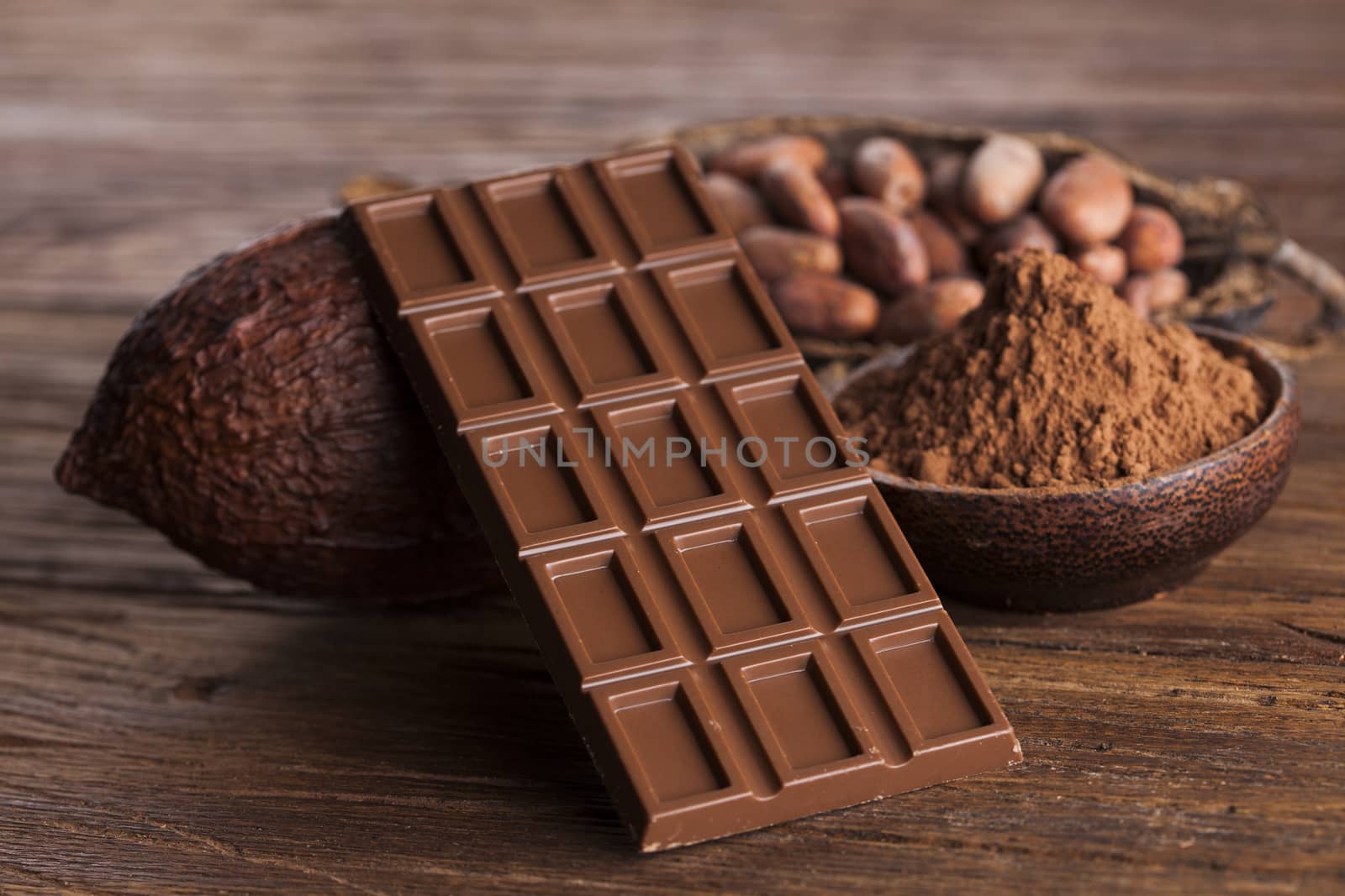 Chocolate bar, candy sweet, cacao beans and powder on wooden background