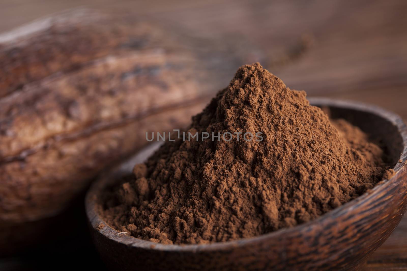 Cocoa beans in the dry cocoa pod fruit on wooden background by JanPietruszka