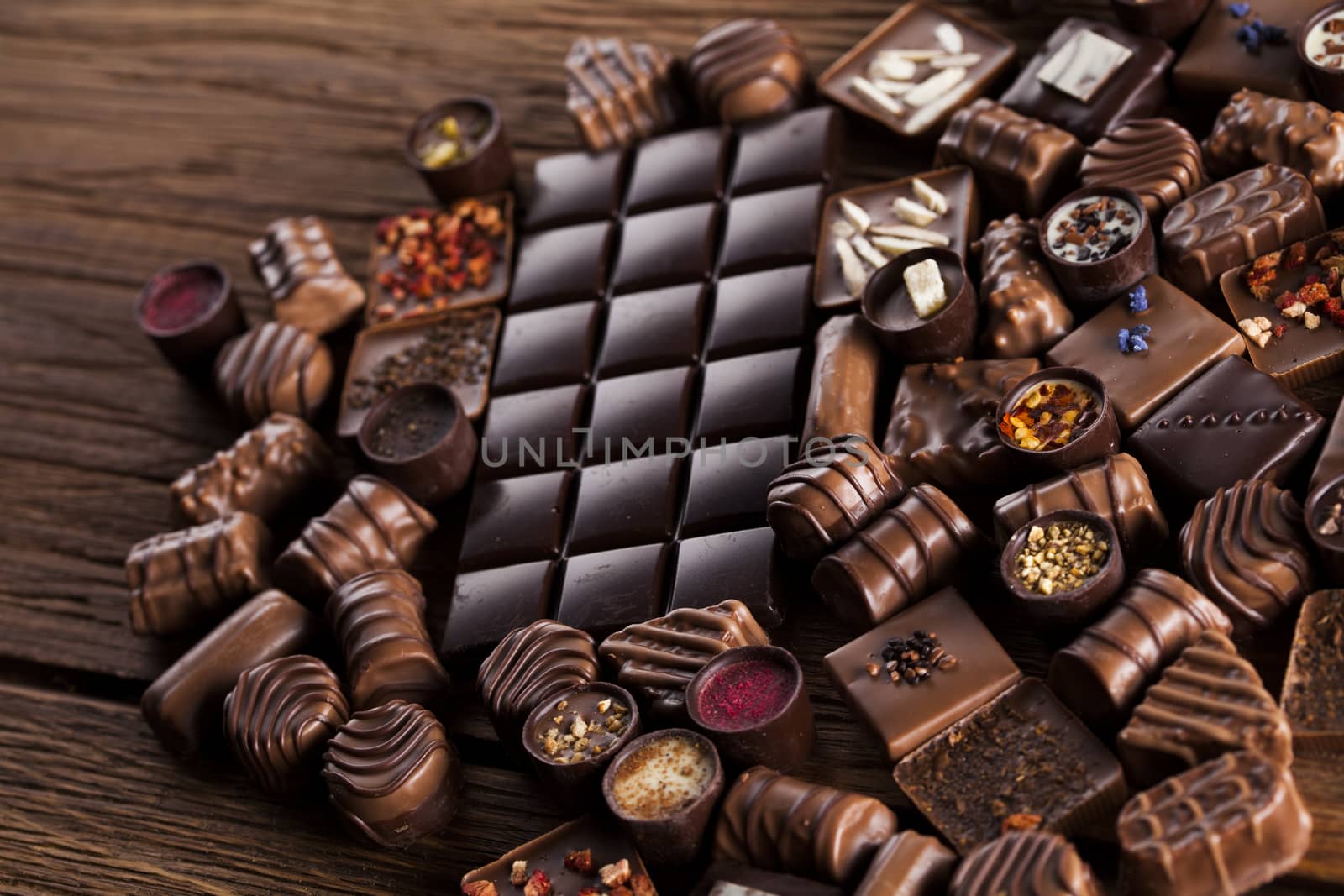Chocolate bars and pralines on wooden background