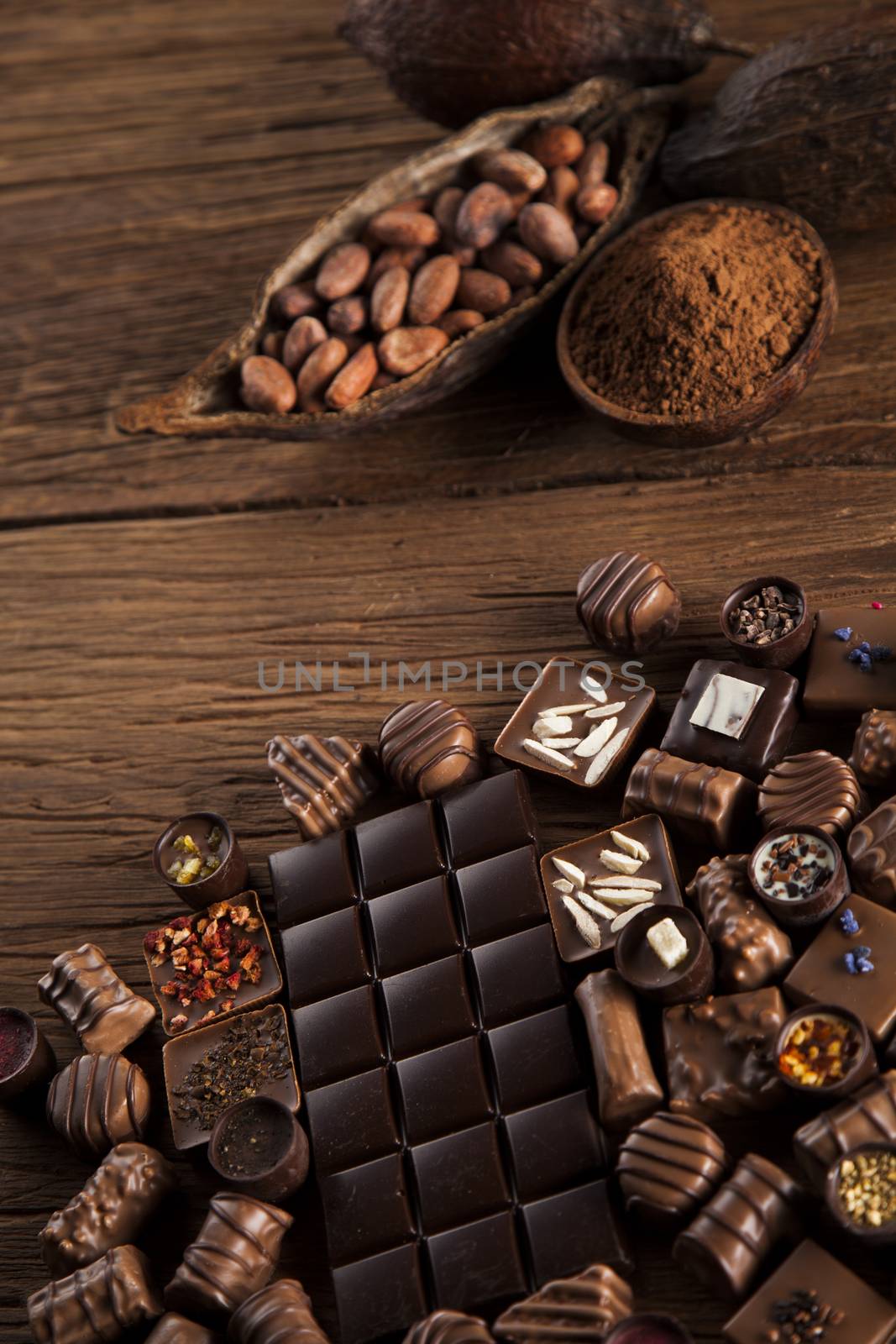 Chocolate bars and pralines on wooden background