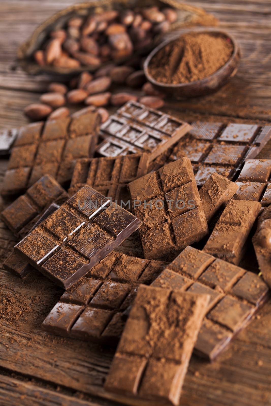 Dark homemade chocolate bars and cocoa pod on wooden