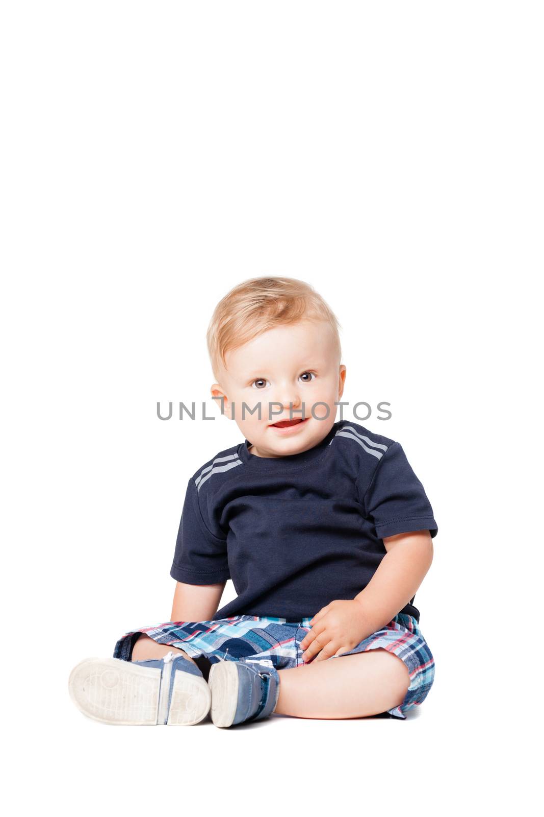 happy baby boy sitting on the floor, isolated on white