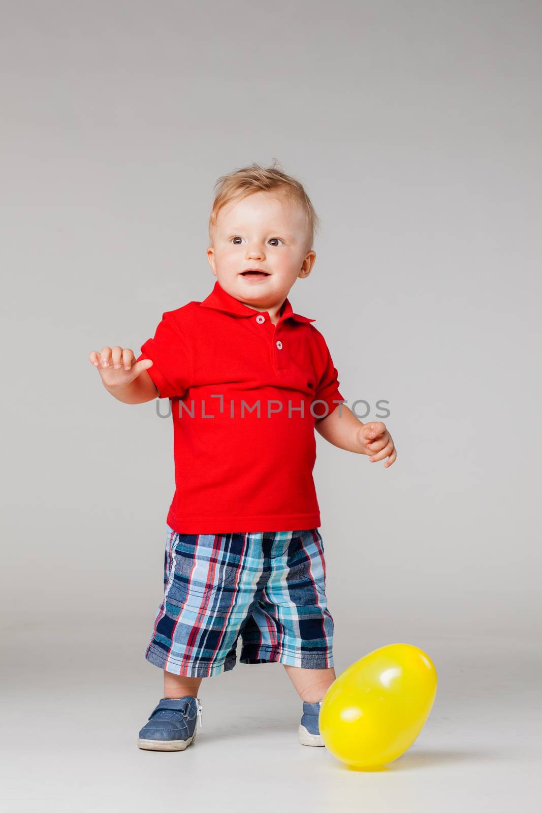 baby boy standing on the floor with a yellow balloon