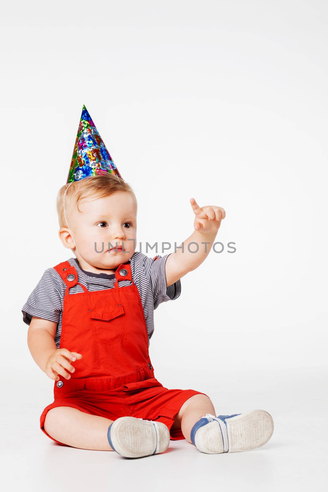 baby boy with birthday hat in overall red shorts