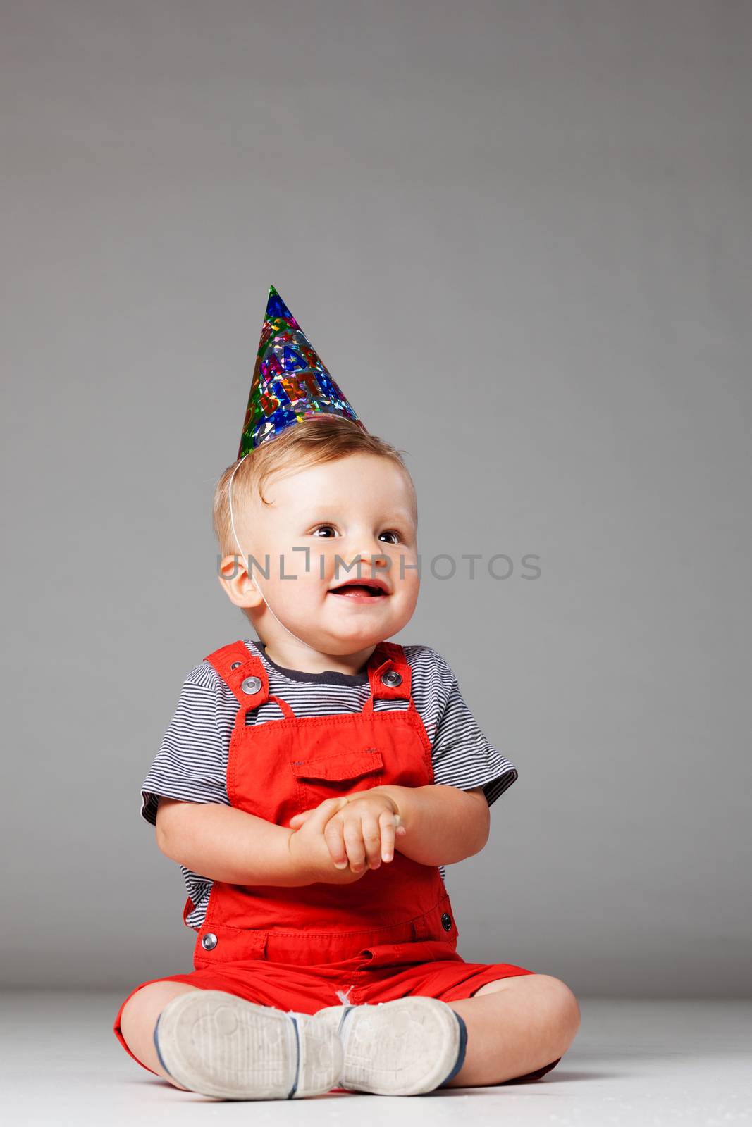 baby boy with birthday hat in overall red shorts