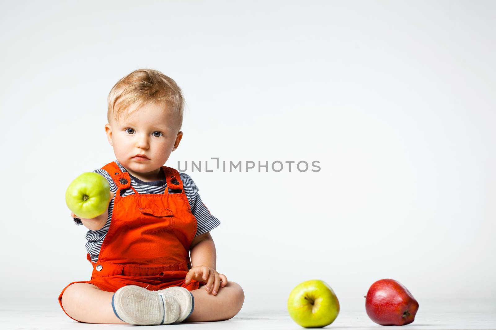 baby boy playing with green and red apples