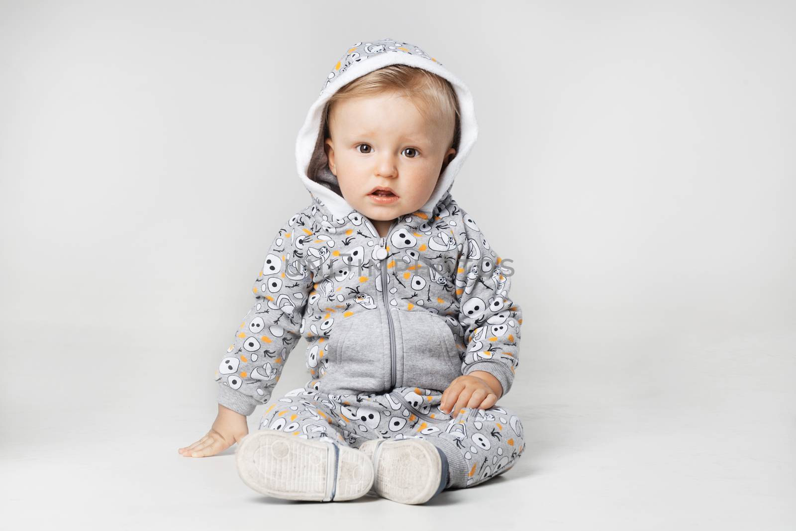 baby boy sitting on the ground, looking at camera, serious expression