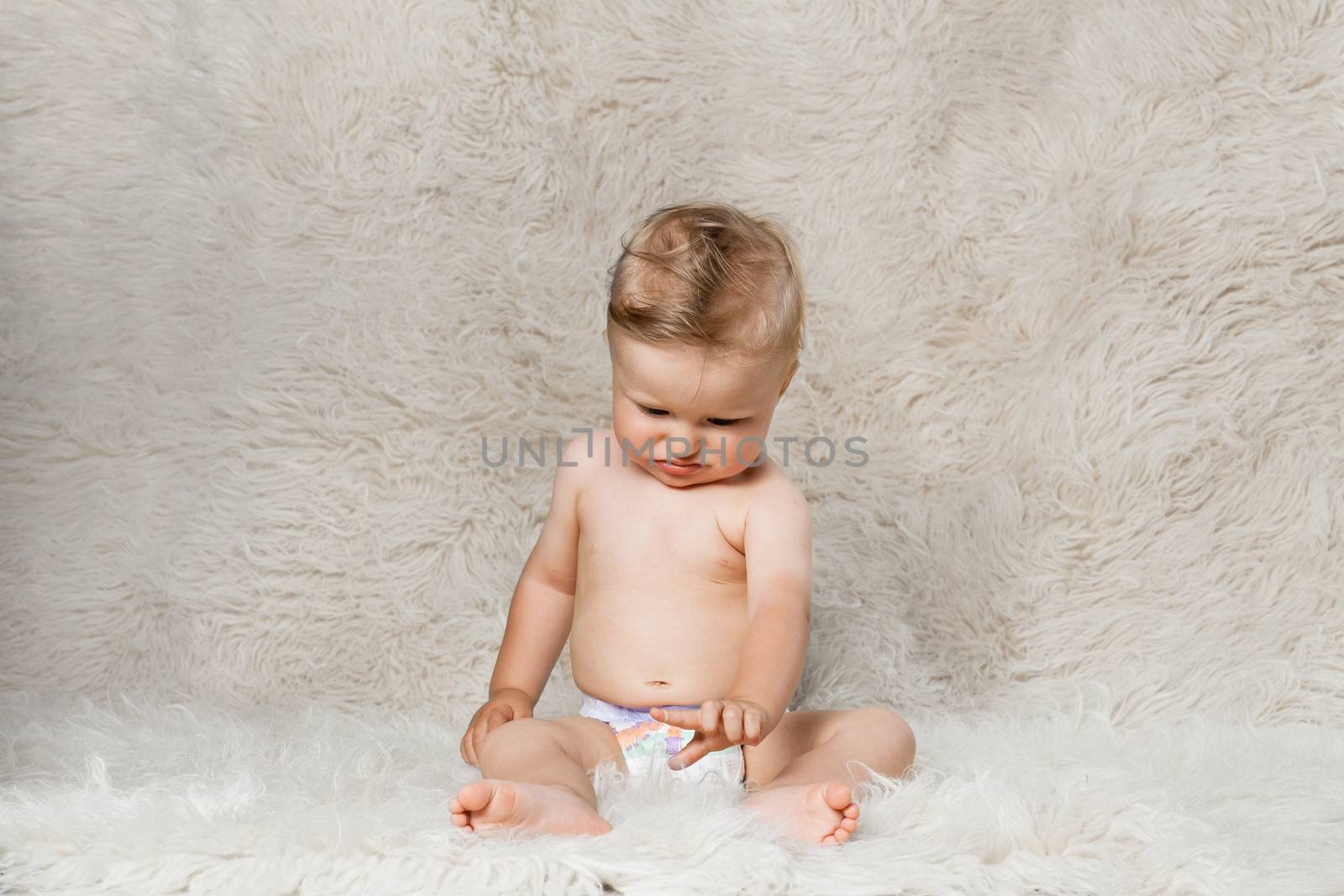 baby boy in diapers, sitting on a shaggy woolen homemade blanket