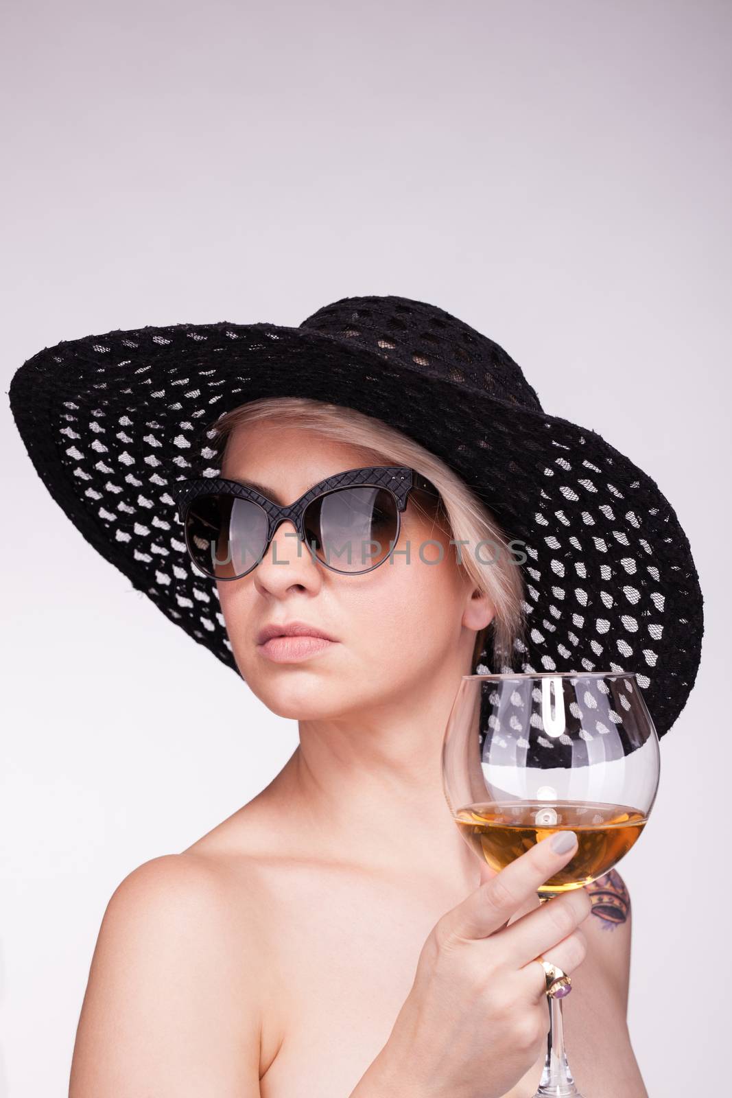 silhouette portrait of a caucasian girl with short hair, hat and glasses, holding wine