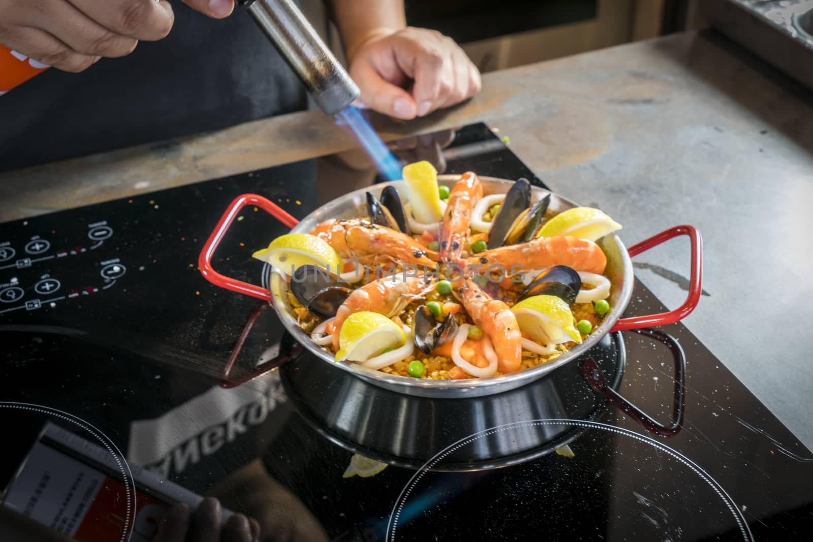 Chef is frying seafood of paella with burner