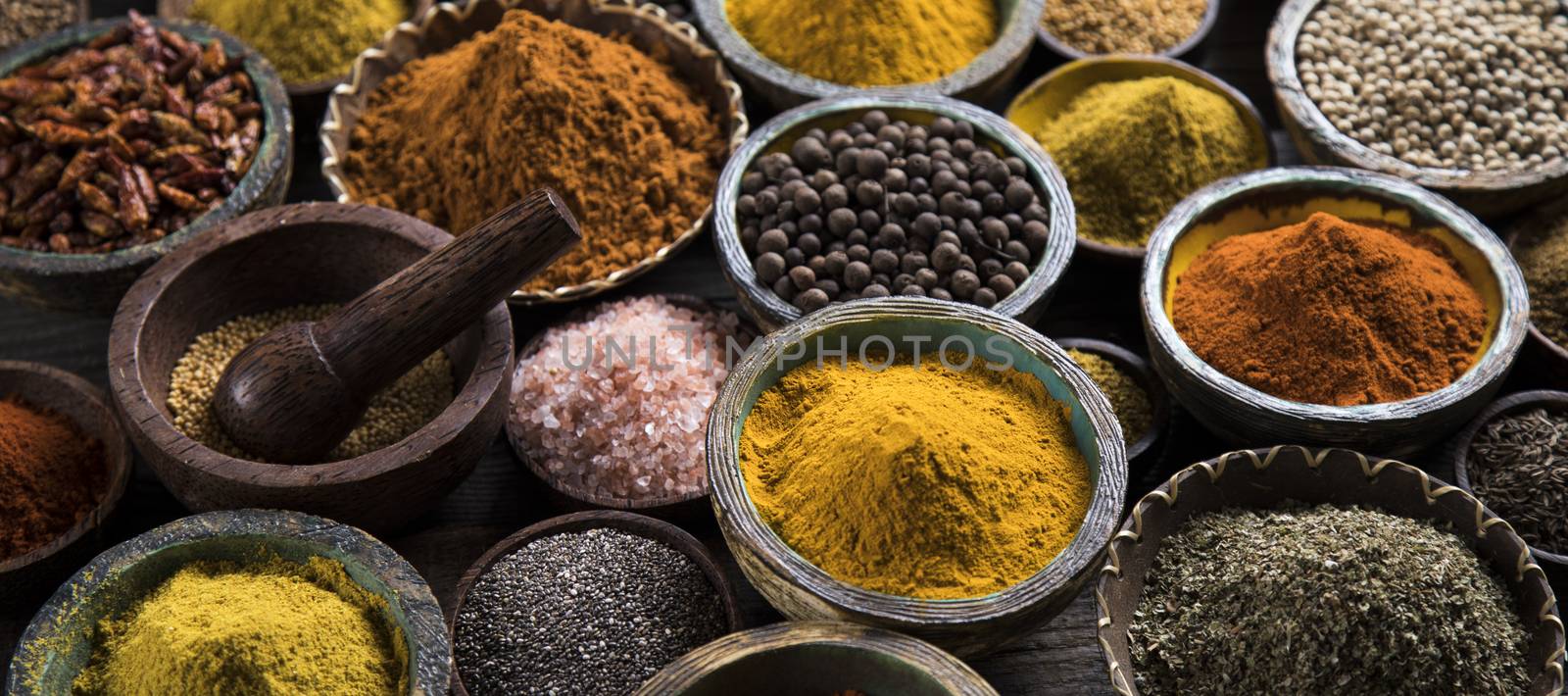 A selection of various colorful spices on a wooden table in bowl by JanPietruszka