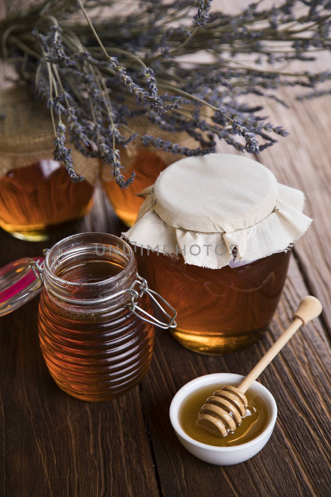 Honey in jar with honey dipper on wooden background