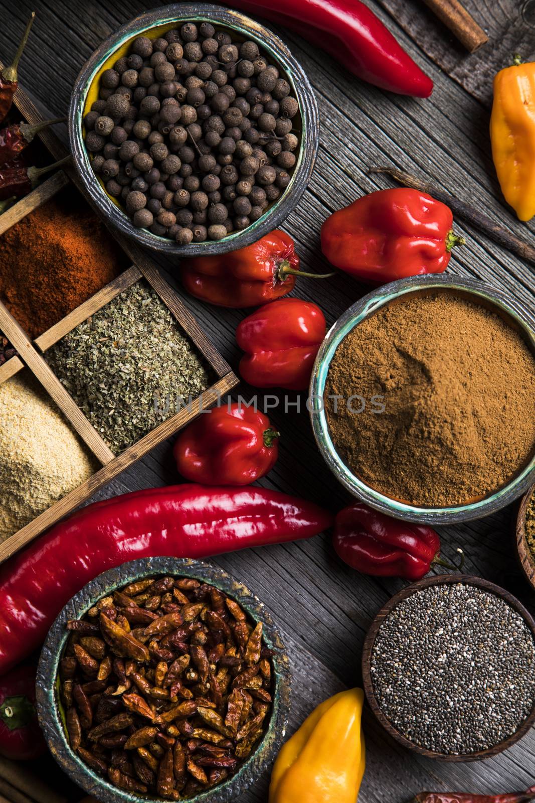 A selection of various colorful spices on a wooden table in bowls