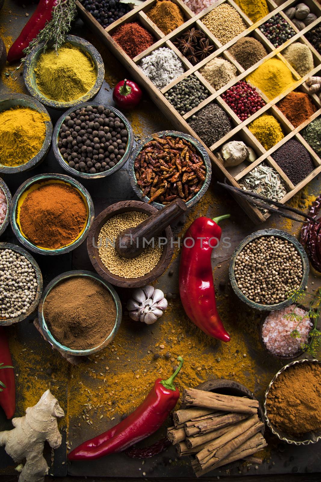 A selection of various colorful spices on a wooden table in bowls