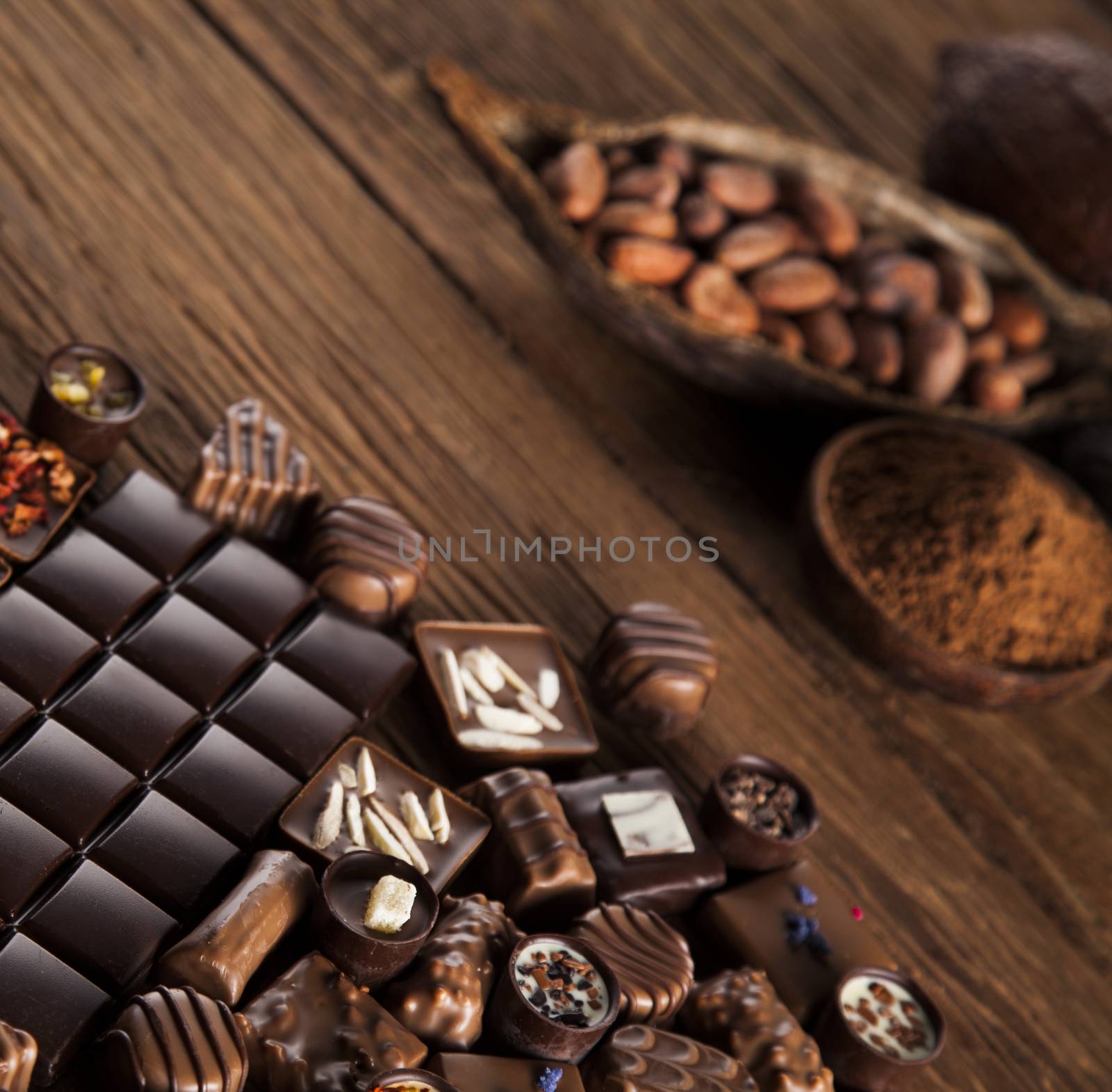 Chocolate bars and pralines on wooden background by JanPietruszka