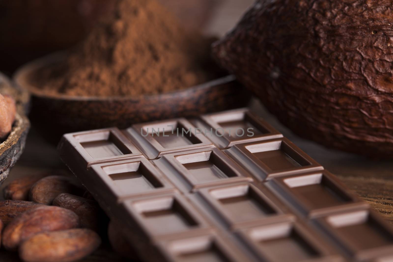 Chocolate bar, candy sweet, cacao beans and powder on wooden bac by JanPietruszka