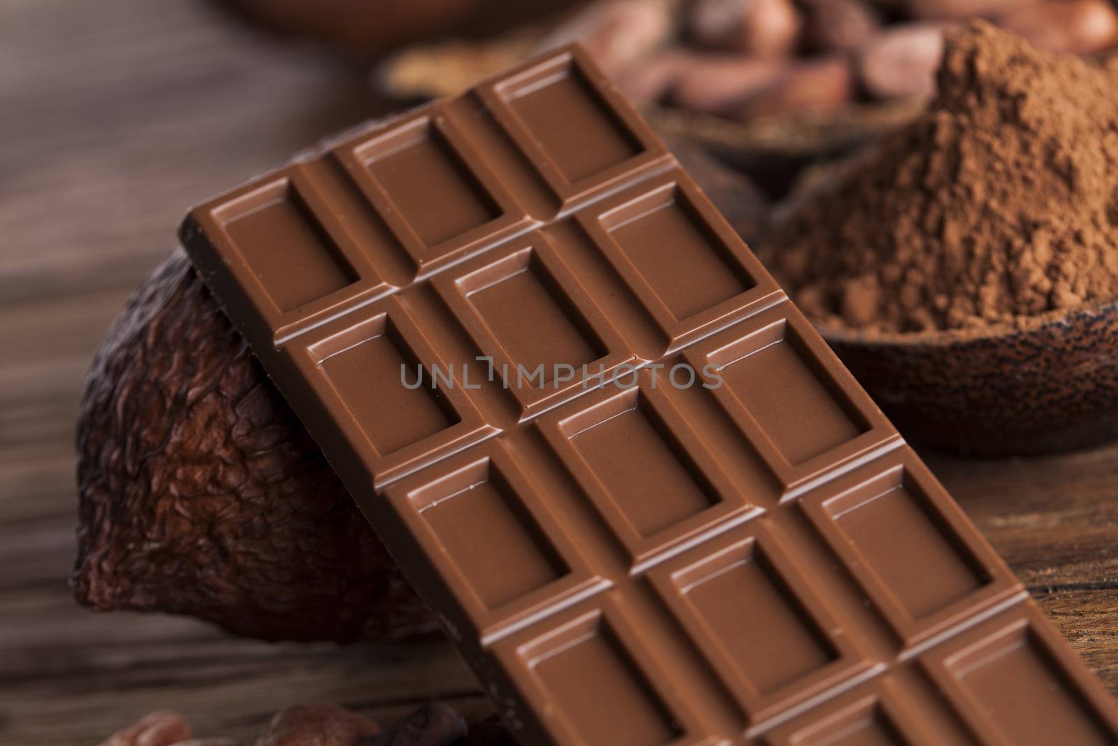 Chocolate bar, candy sweet, cacao beans and powder on wooden background