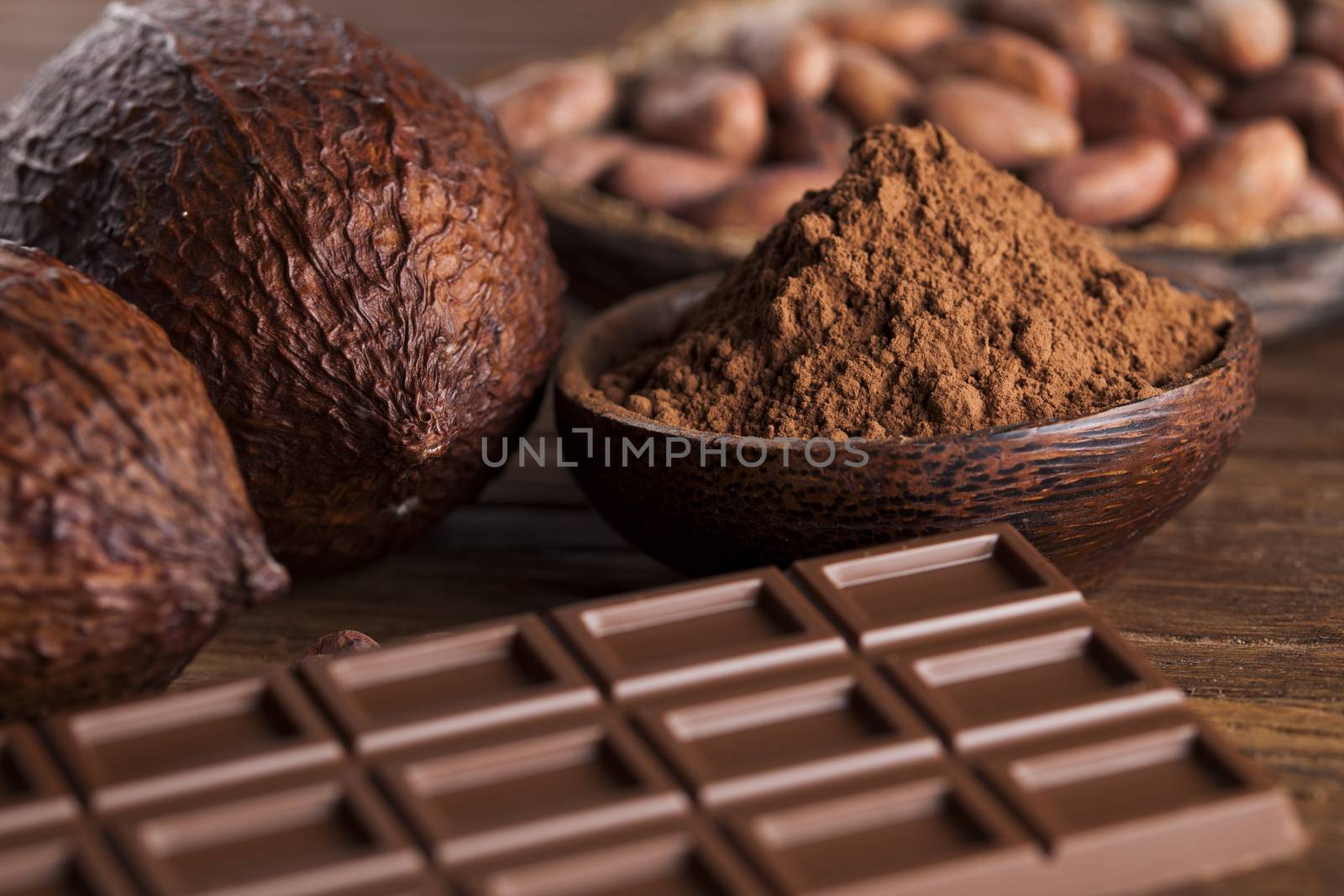 Chocolate bar, candy sweet, cacao beans and powder on wooden background