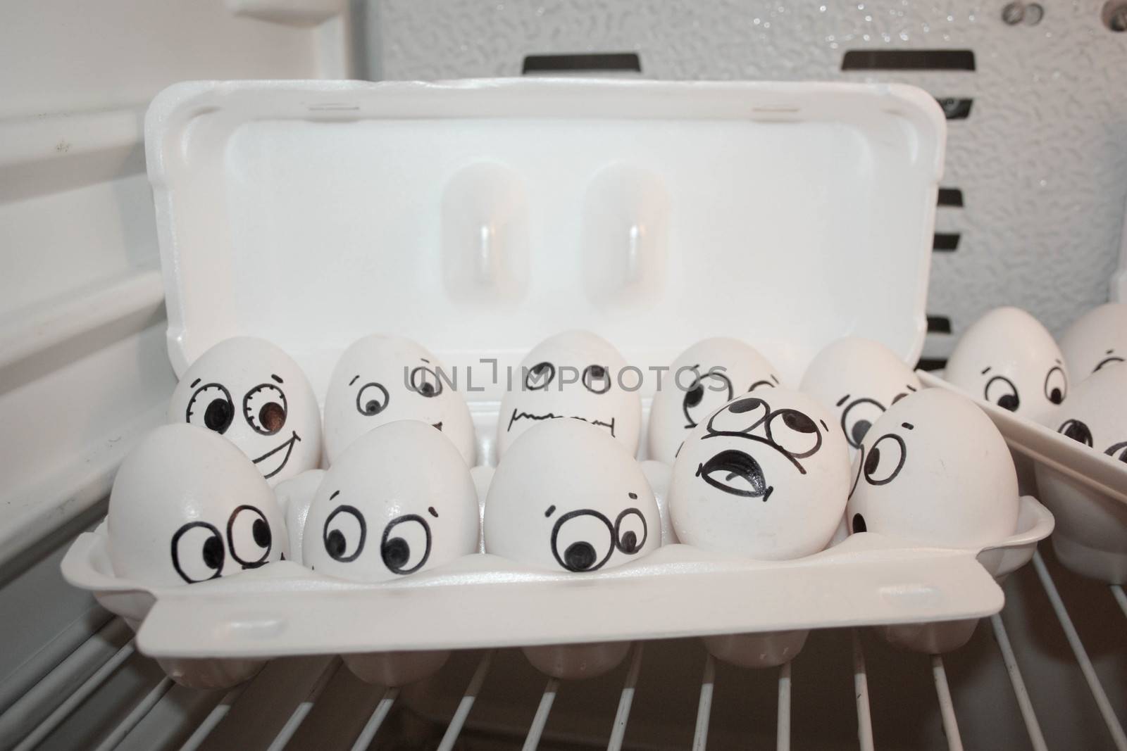 Concept of expectation. Face eggs are funny in the fridge. Photo for your design. Eggs in the container