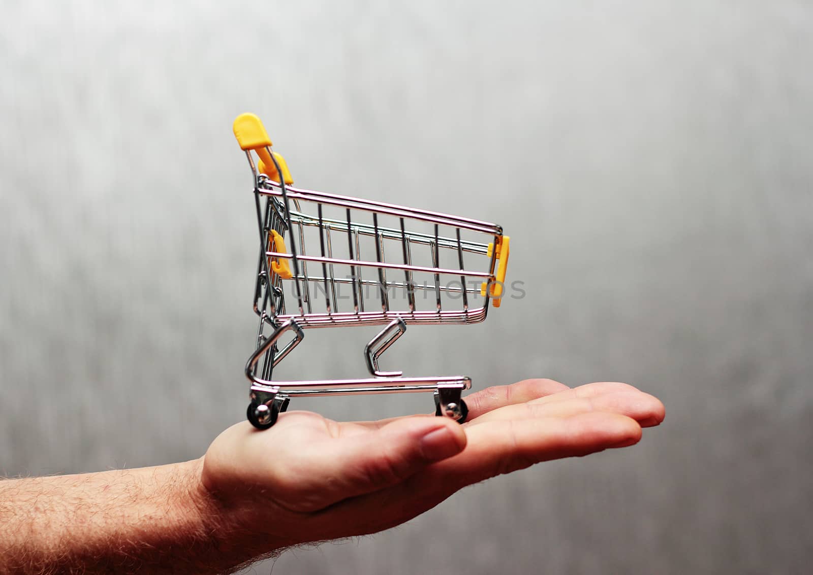 A man's hand holds a miniature food cart isolated with a neutral background.