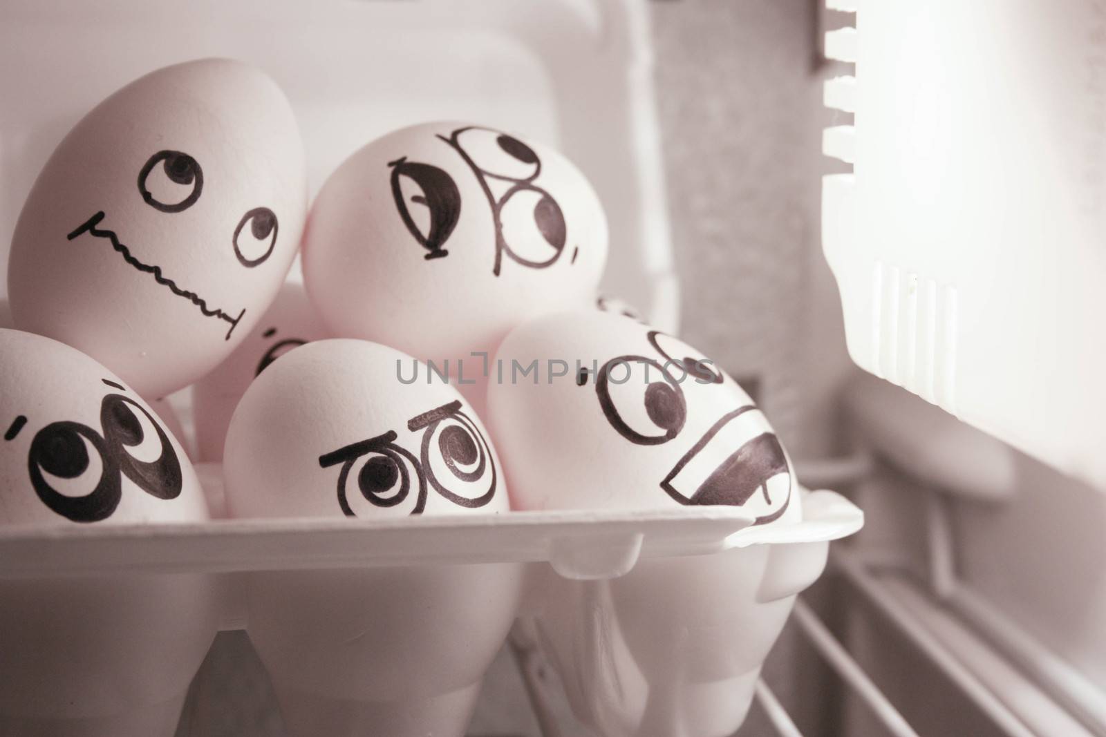 Concept of heat. Face eggs are funny in the fridge. Photo for your design. The eggs are warm with the light.