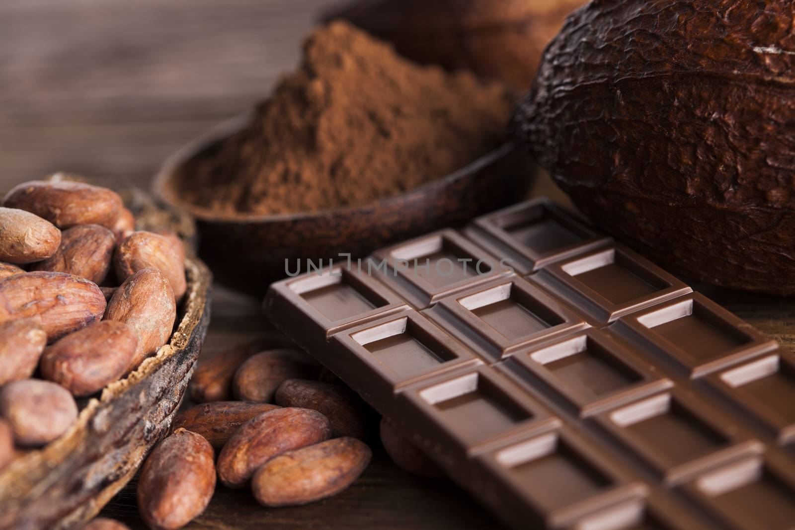 Chocolate bar, candy sweet, cacao beans and powder on wooden bac by JanPietruszka