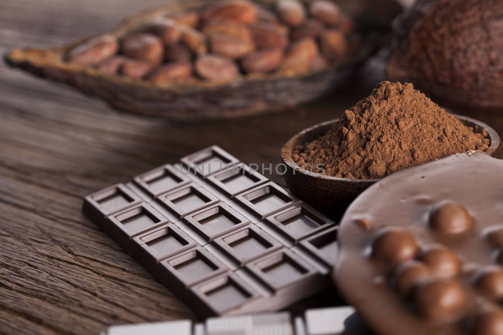 Chocolate bar, candy sweet, cacao beans and powder on wooden bac by JanPietruszka