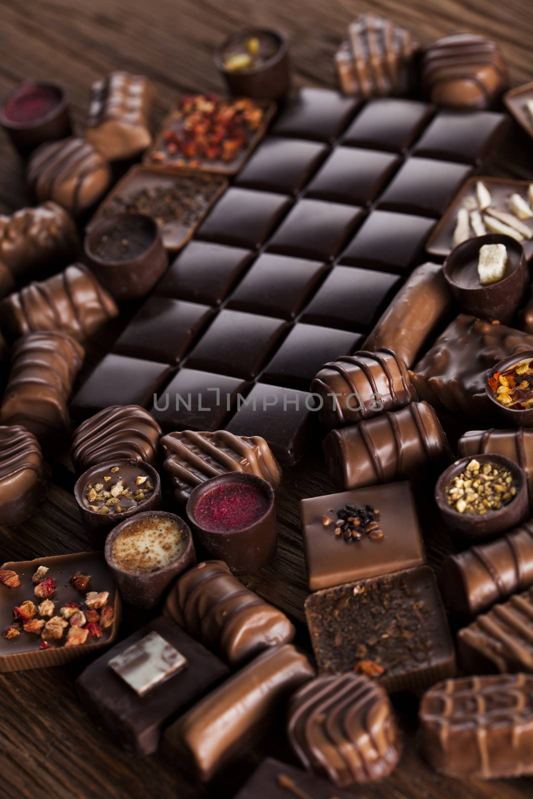 Chocolate bars and pralines on wooden background by JanPietruszka