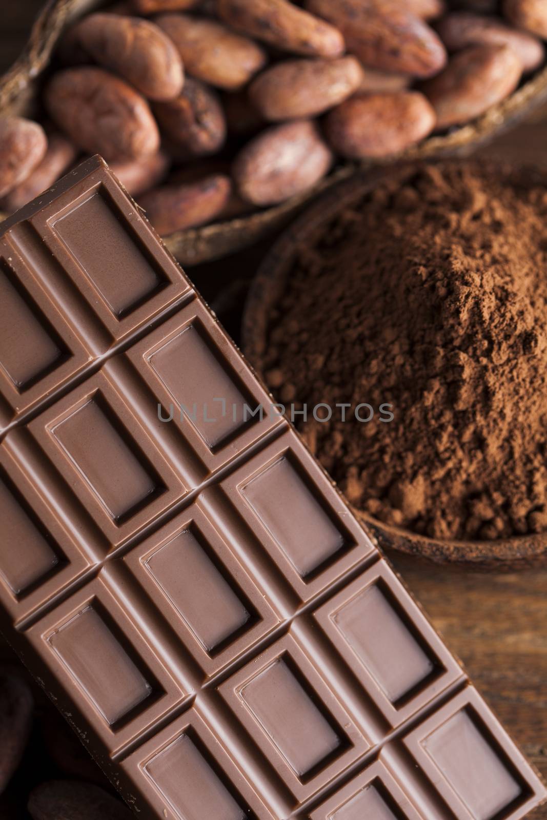 Chocolate bar, candy sweet, cacao beans and powder on wooden background