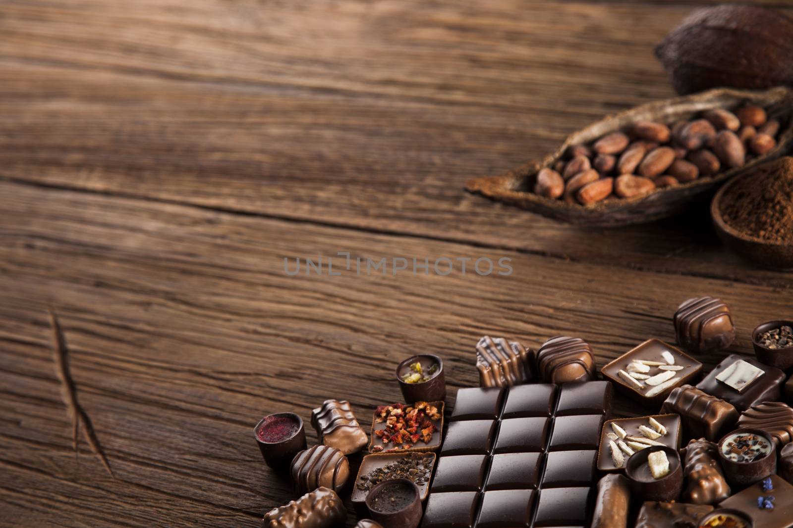 Chocolate bars and pralines on wooden background by JanPietruszka