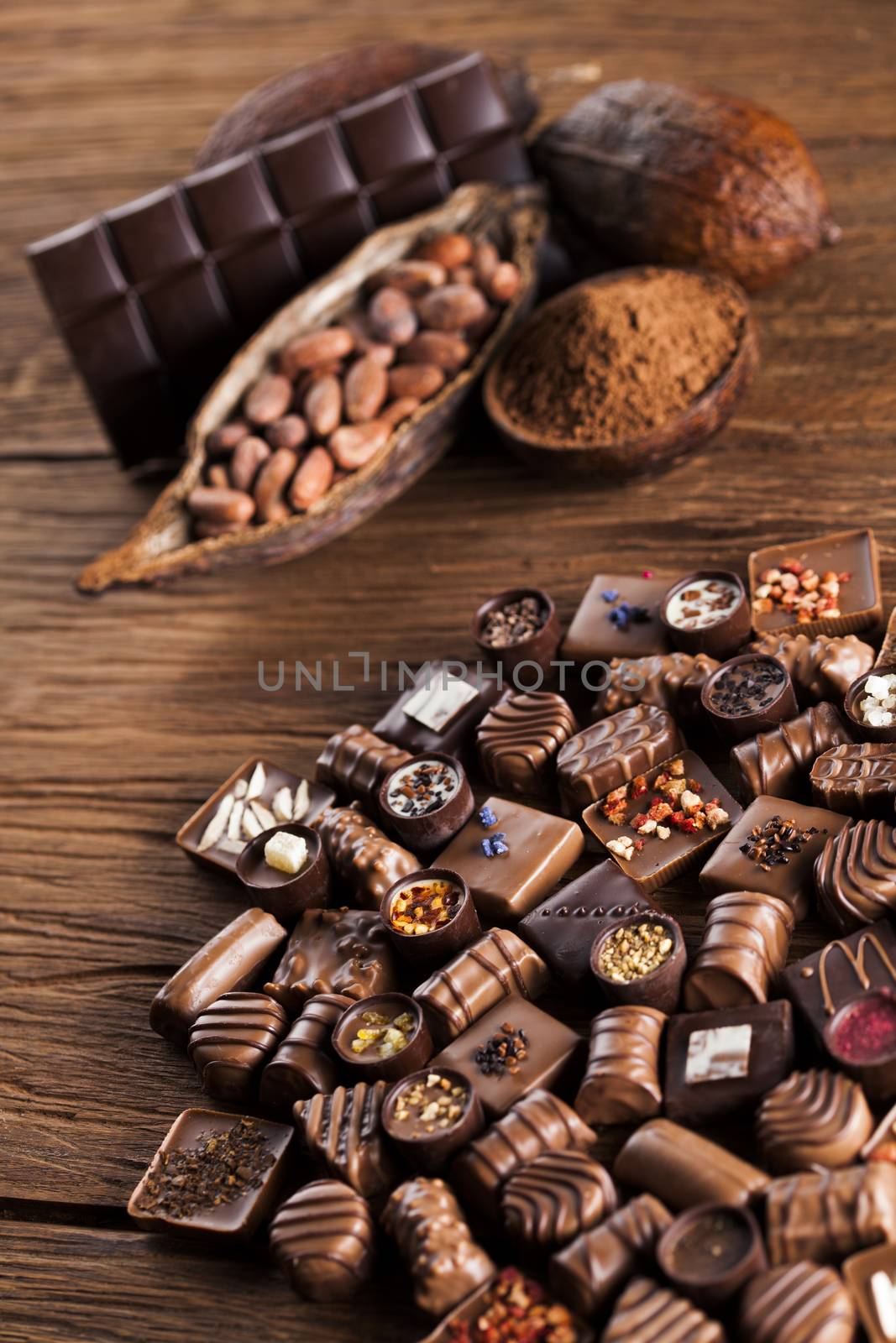 Chocolate bars and pralines on wooden background by JanPietruszka