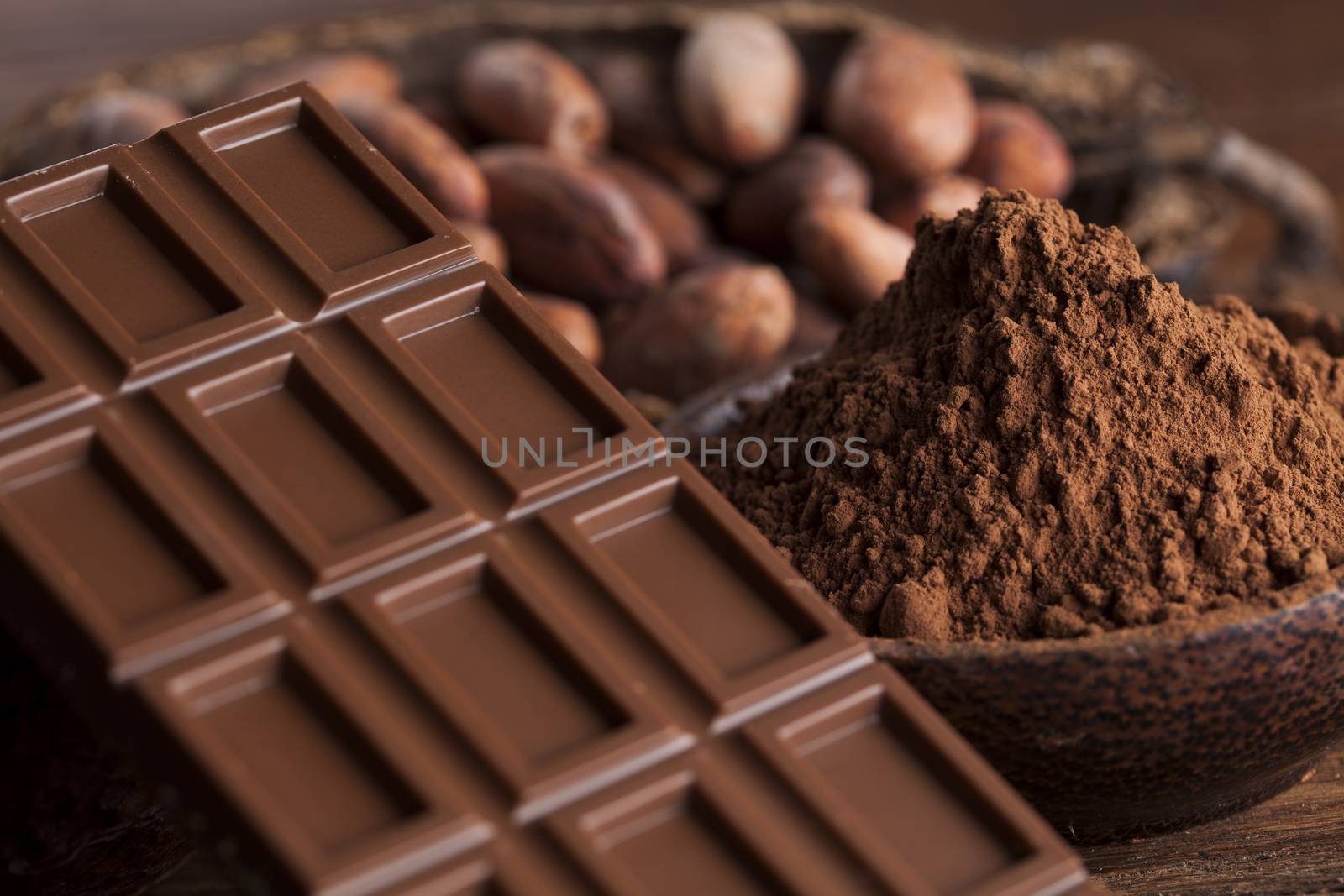 Chocolate bar, candy sweet, cacao beans and powder on wooden bac by JanPietruszka