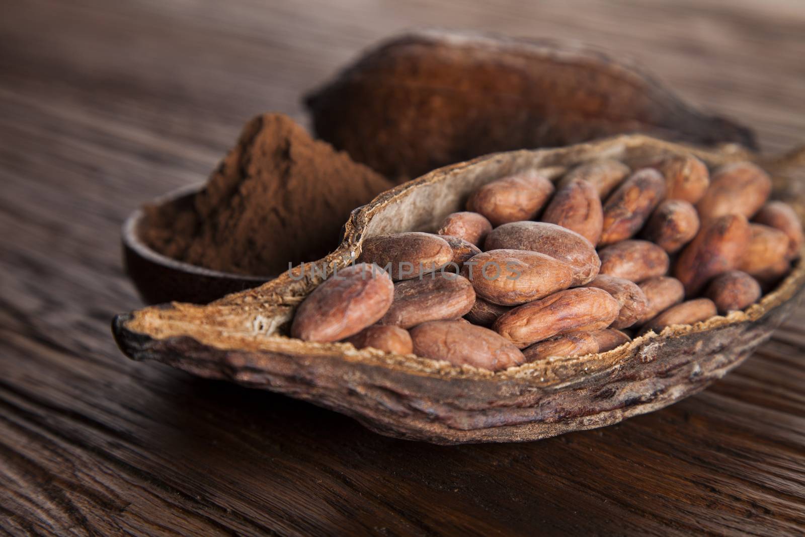 Cocoa beans in the dry cocoa pod fruit on wooden background by JanPietruszka
