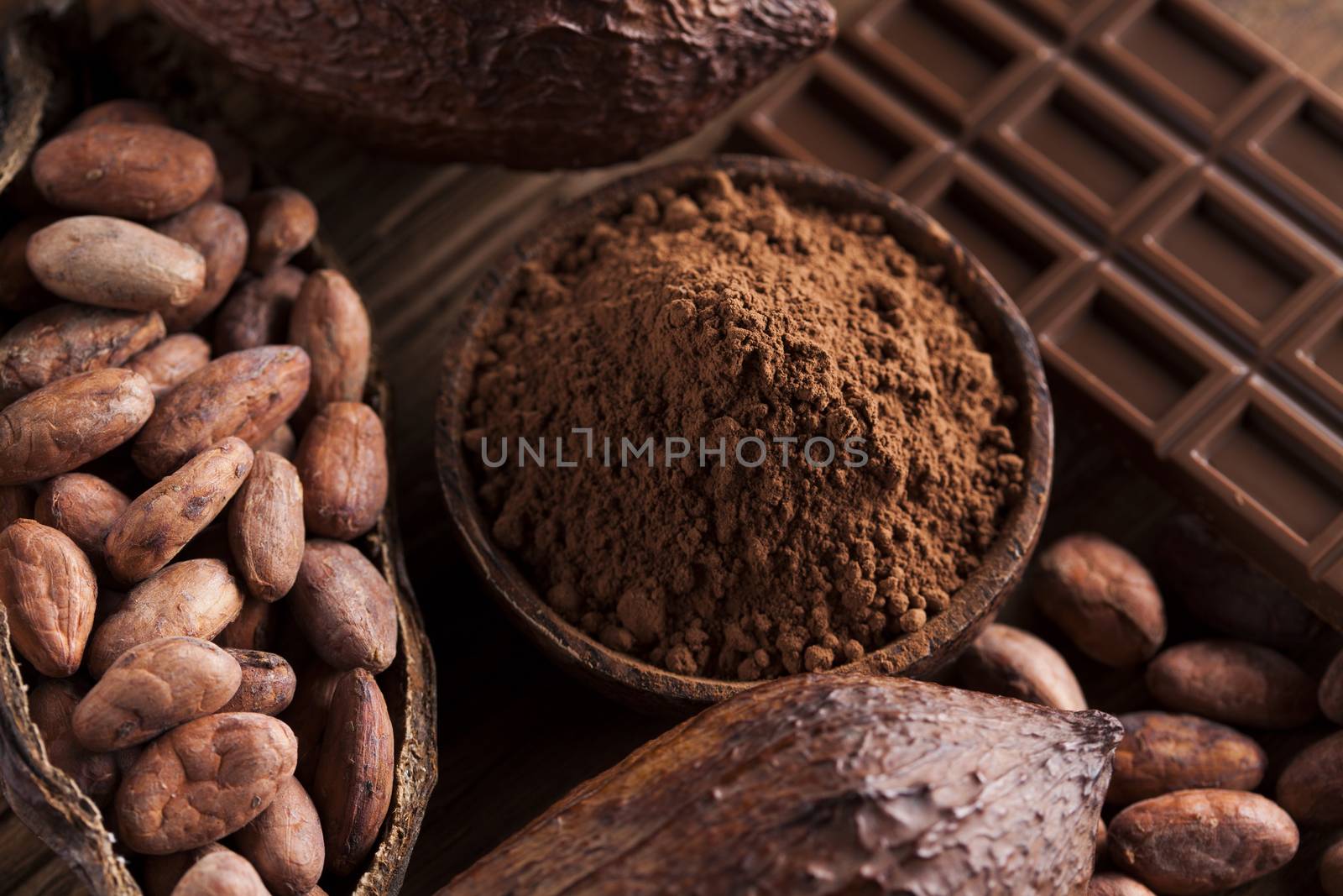 Chocolate bar, candy sweet, cacao beans and powder on wooden background