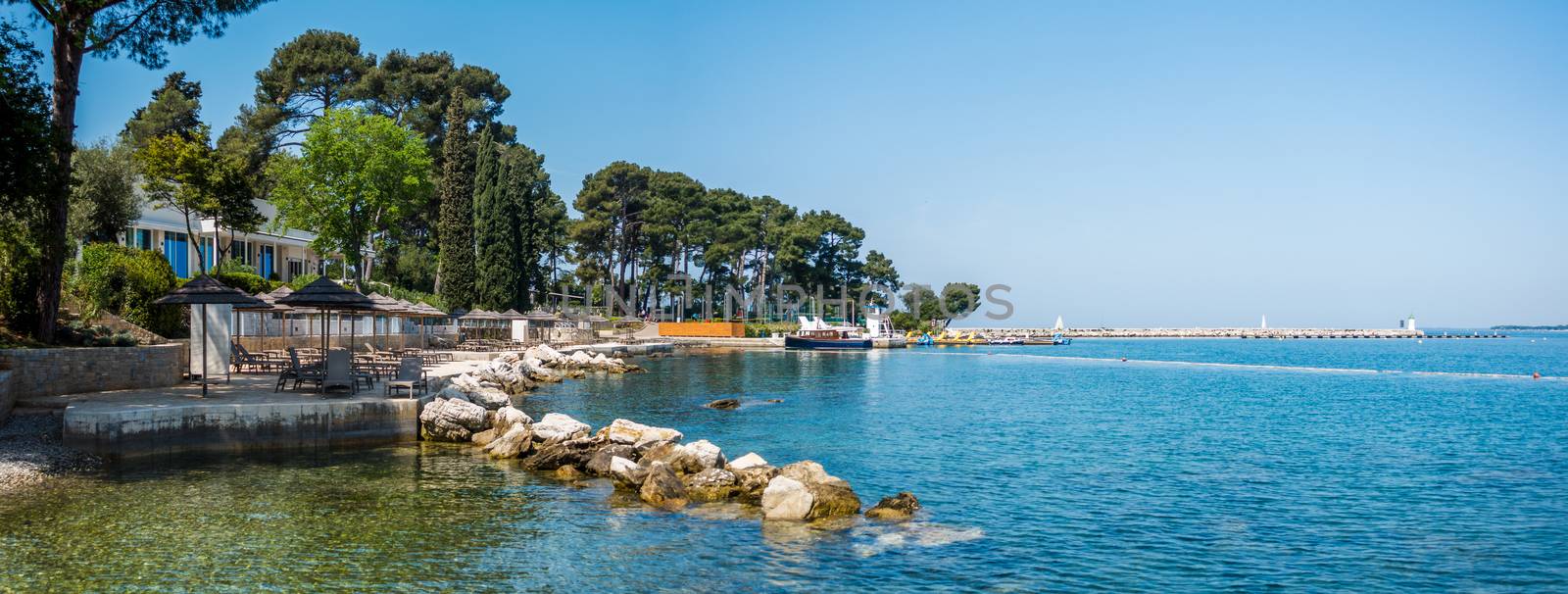 Beach and resort with beach chairs in morning light on the beach of a Croatian seaside holiday resort in Porec, Istria, no people