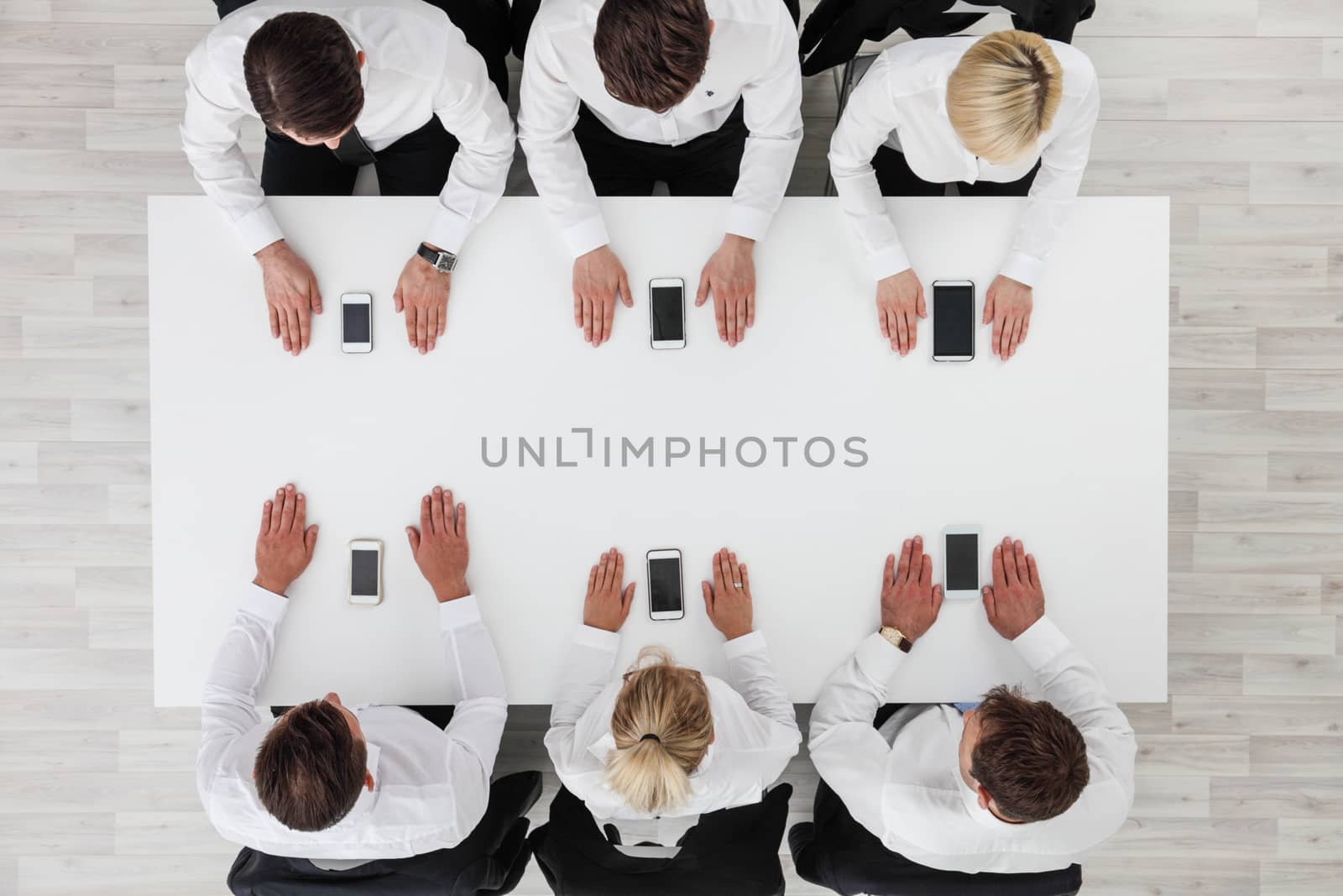 Business people not using smartphones sitting around white table